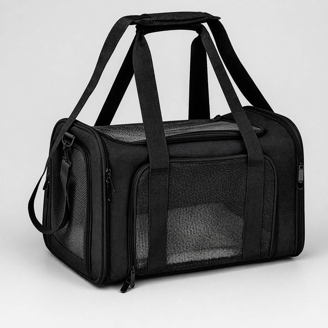 Black soft-sided pet carrier bag with mesh panels and carry handles on a light gray background