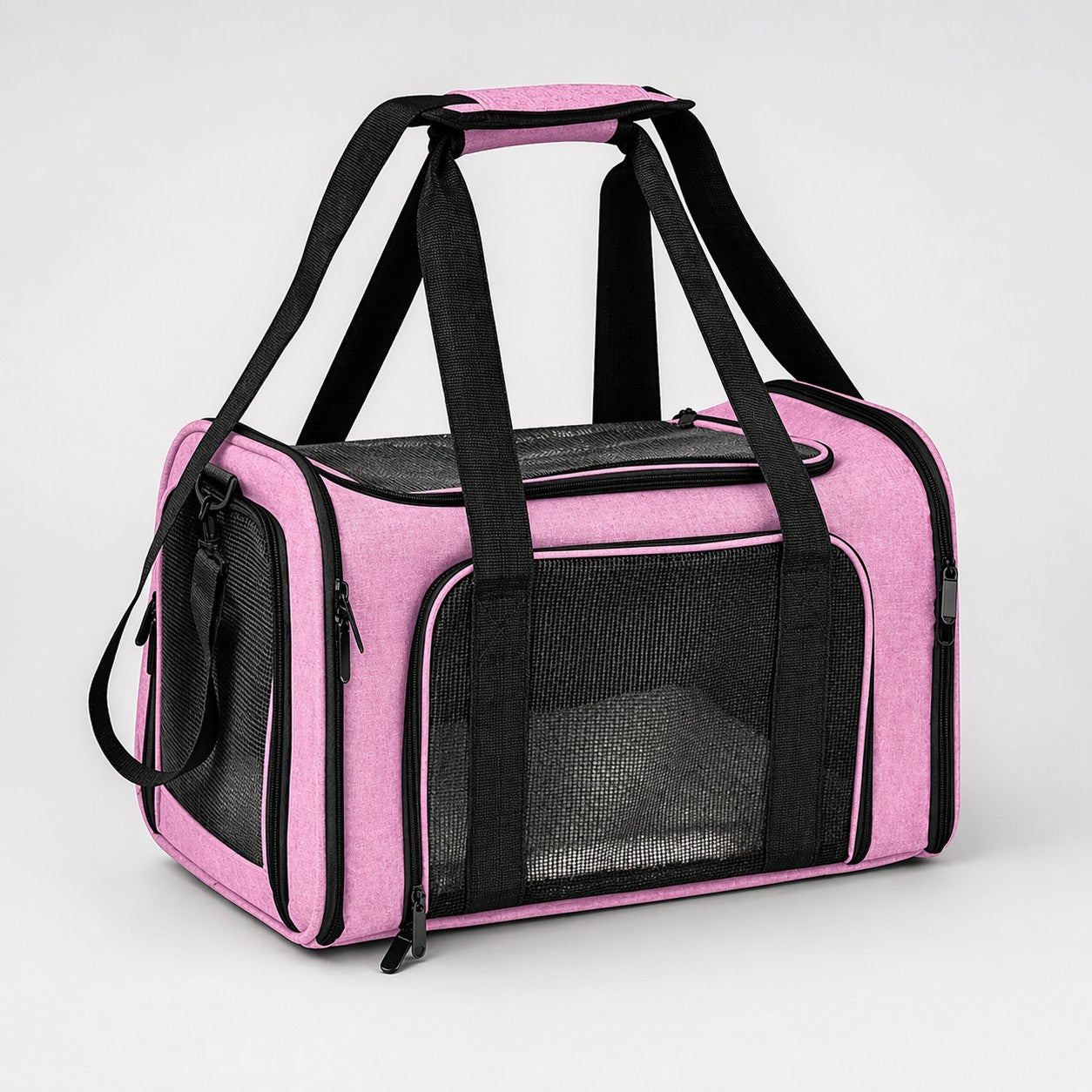 Pink soft-sided pet carrier bag with mesh panels and black carry handles on a light gray background